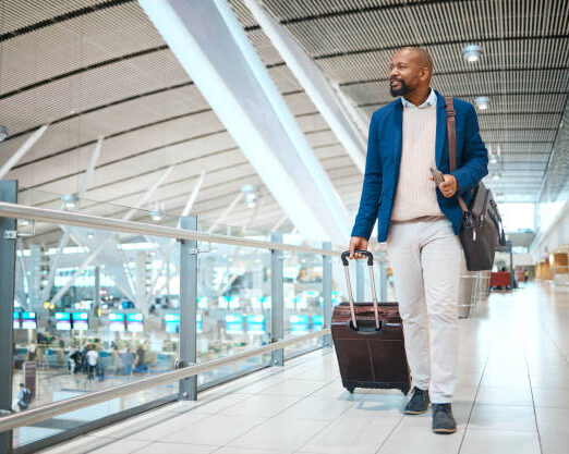 Travel, airport and luggage with a business black man walking in a terminal for global success. Manager, mockup and flight with a male ceo in a terminus station for international work traveling